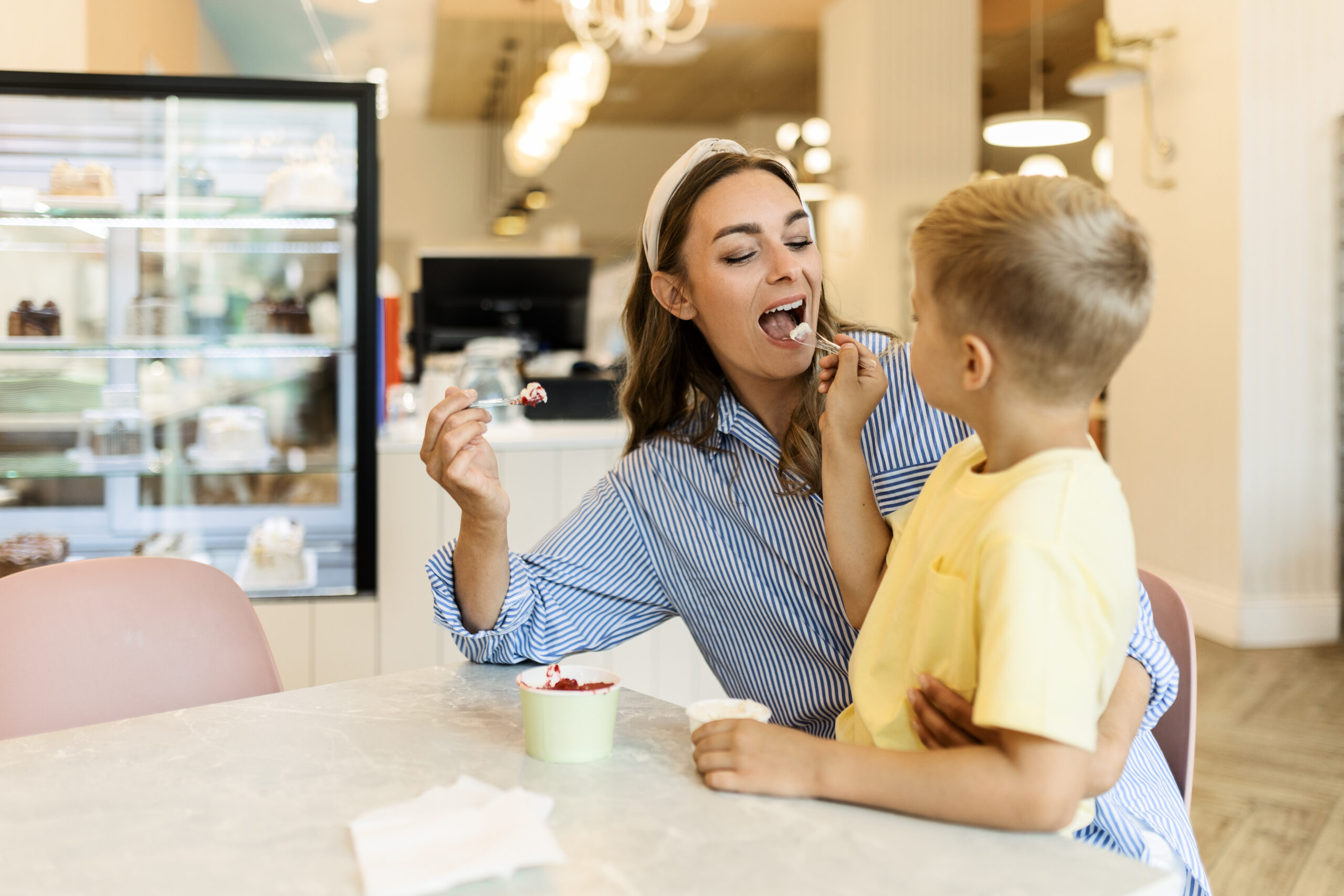 Mother and son sharing ice cream in an ice cream parlor.