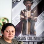 Ada Bell Baquedano-Amador stands next to a poster of her son Emerson Colindres